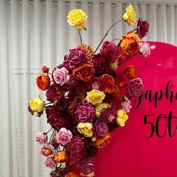 Vibrant floral backdrop with roses in pink, yellow, orange, and purple for celebrations.