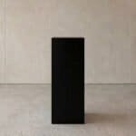 Simple black pedestal stand for displaying art or decor items.