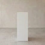 White pedestal display stand in modern interior setting for decor or product showcase.